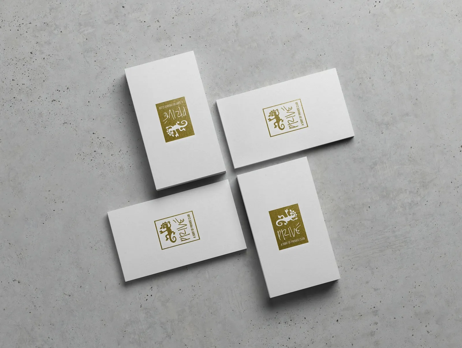 Prive white business cards with gold gecko foil logo arranged on grey concrete